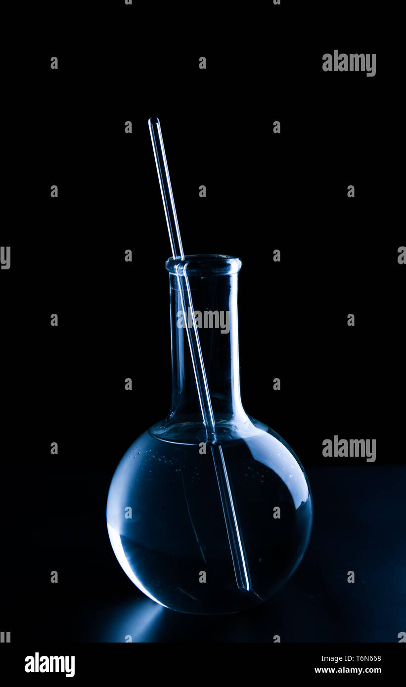 Fiole jaugée avec pipette et liquide sur fond noir Banque D'Images