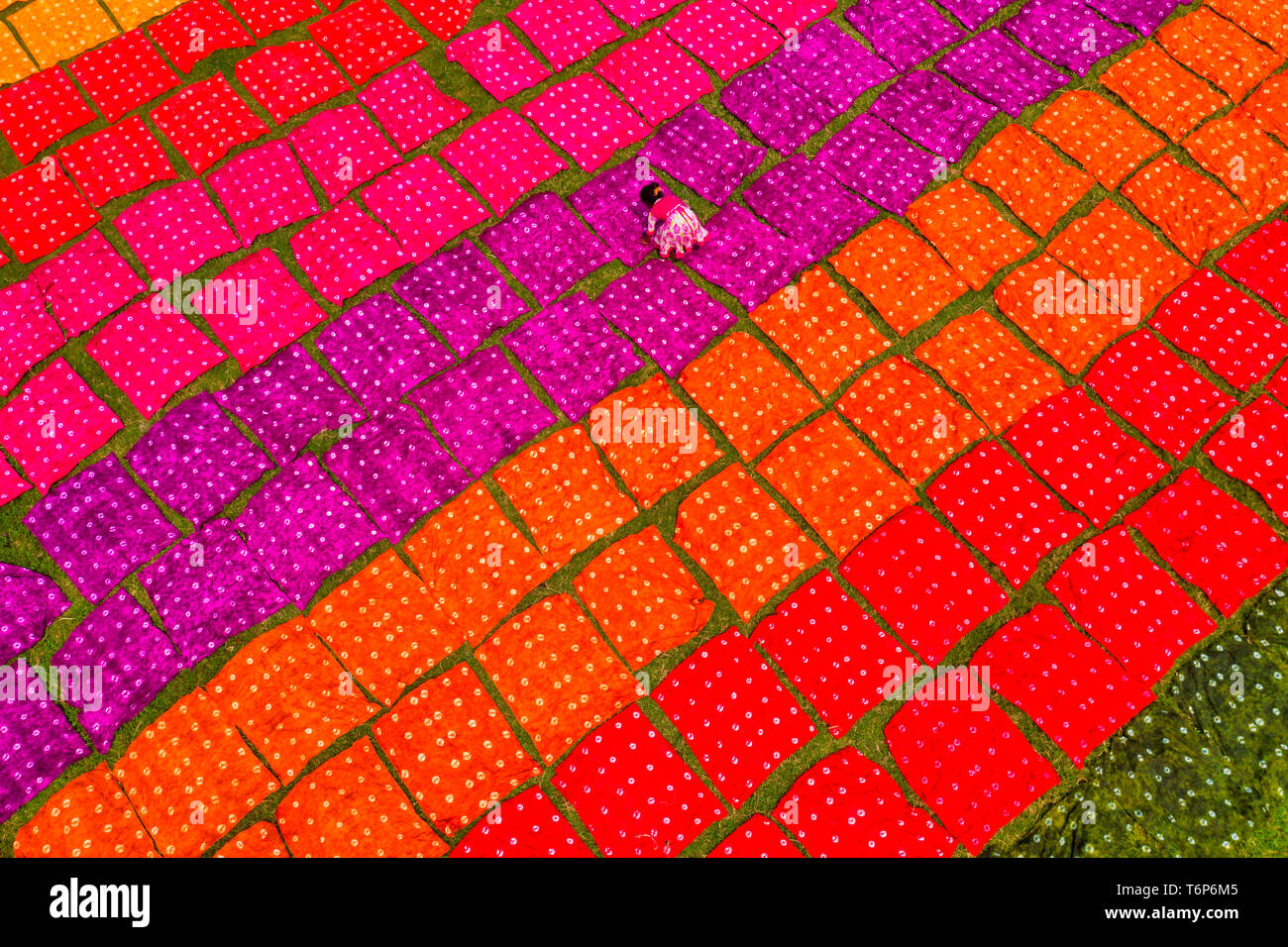 NOTE DU RÉDACTEUR : Image prise avec drone) Ouvriers vu le dépliage des  centaines de mètres de tissu rouge brillant teints fraîchement sur un  terrain dans le cadre du processus de création