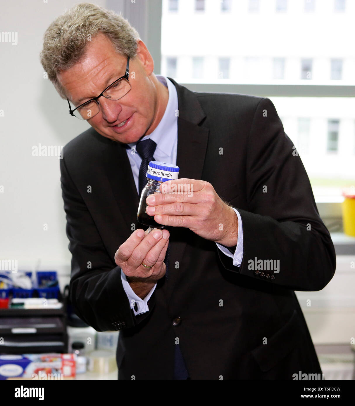 02 mai 2019, le Schleswig-Holstein, Lübeck : Bernd Buchholz (r, FDP), de l'économie Ministre du Schleswig-Holstein, est titulaire d'un verre rempli de liquide magnétique dans ses mains. Le jeudi, l'homme politique a présenté l'Université de Lübeck avec une décision de financement pour près de 540000 euros. L'argent est destiné à l'établissement d'un laboratoire à l'Institut de robotique et systèmes cognitifs et de la technologie médicale. Photo : Frank Molter/dpa Banque D'Images