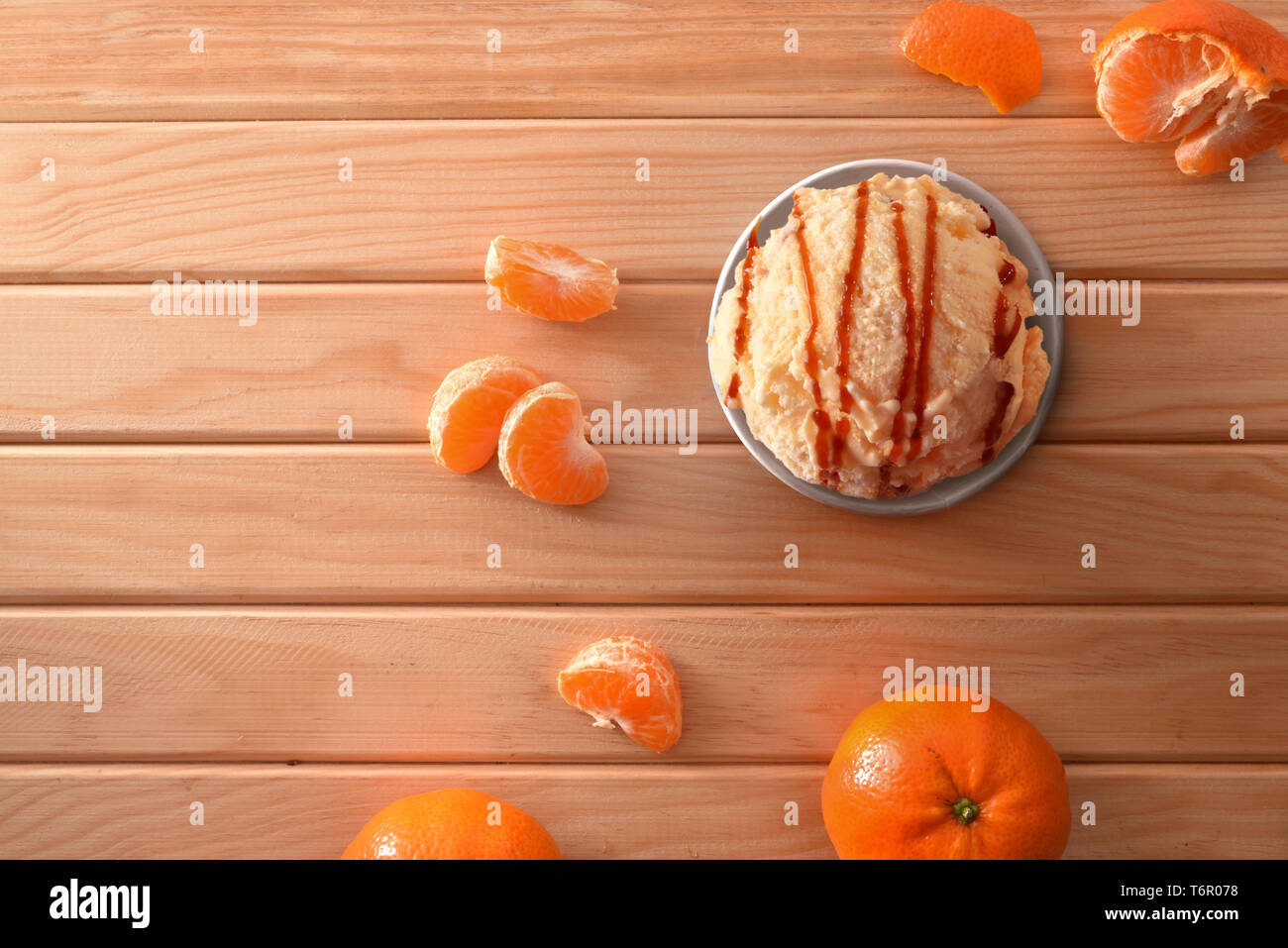 La crème glacée Mandarin tasse décorée avec des segments de mandarines sur une table en bois. Composition horizontale. Vue d'en haut. Banque D'Images