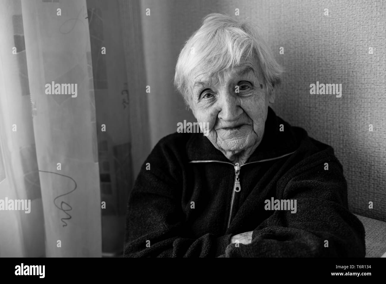 Portrait noir et blanc d'une vieille femme dans sa chambre. Soins pour personnes âgées solitaires. Banque D'Images