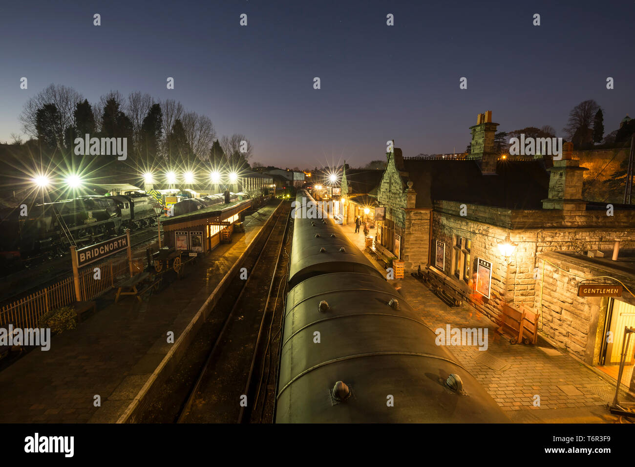 Vue nocturne à angle élevé de la gare de Bridgnorth rétro éclairée par une soirée froide et sombre. Les projecteurs montrent les locomotives à vapeur et diesel sur les voies de garage. Banque D'Images