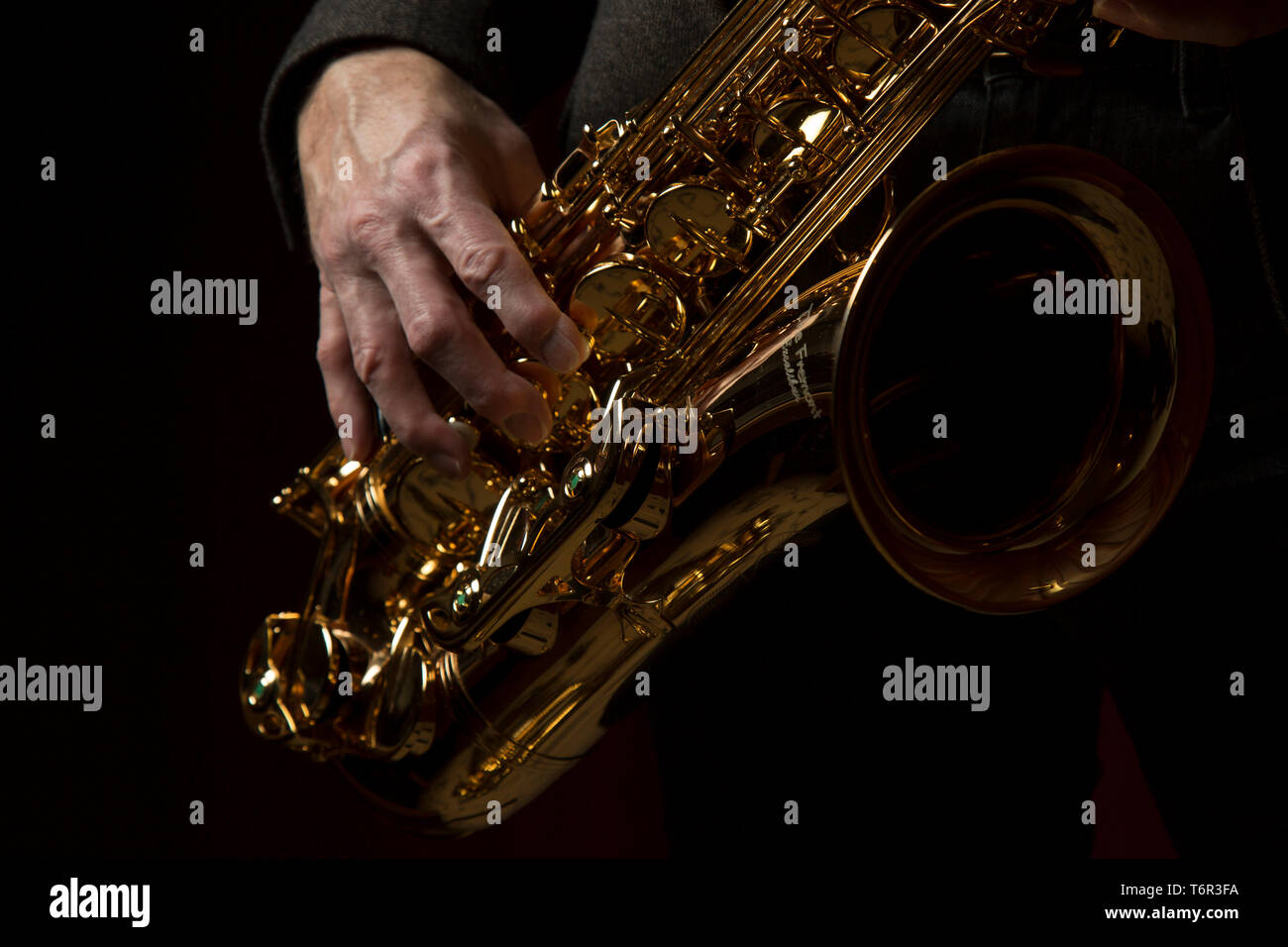 Gros plan sur le saxophone ténor joué par un musicien masculin caucasien, sa main droite en position sur l'instrument. Saxophoniste isolé. Banque D'Images