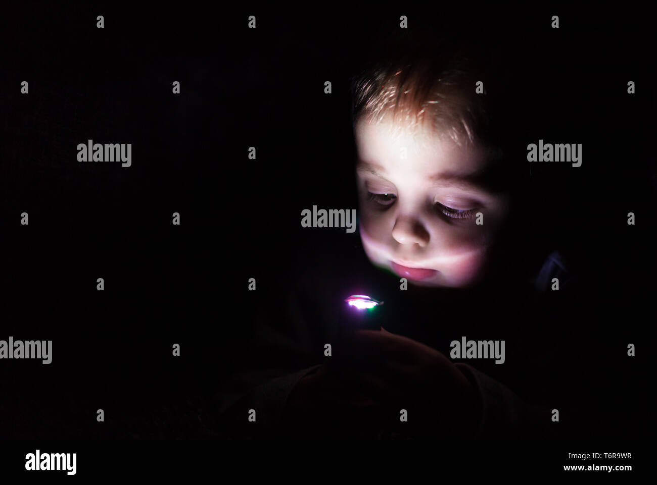 Garçon jouant avec lampe de poche dans le noir Photo Stock - Alamy