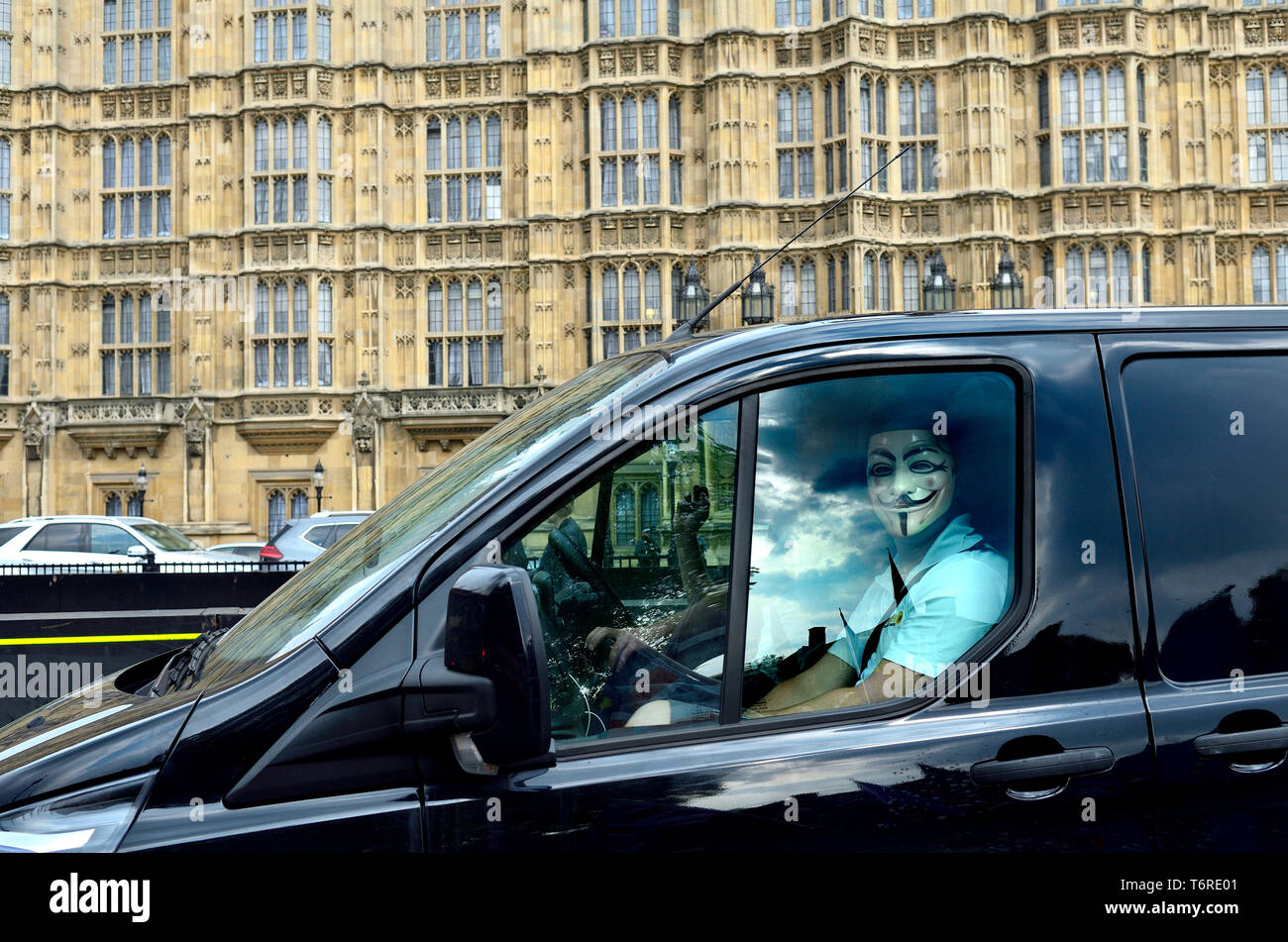 Londres, Angleterre, Royaume-Uni. Un homme portant un masque de V pour Vendetta dans le siège passager d'un van, en passant devant les Chambres du Parlement Banque D'Images