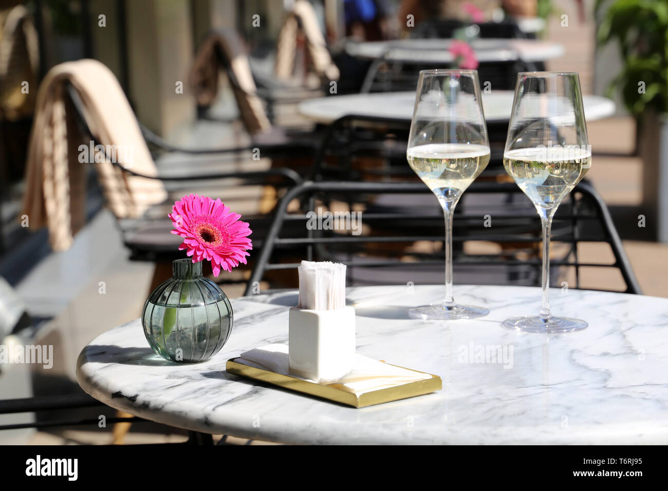 Set de table dans un restaurant de rue, repas romantique et élégant pour la célébration et la date. Deux verres de champagne, de serviettes et de fleurs sur une table Banque D'Images