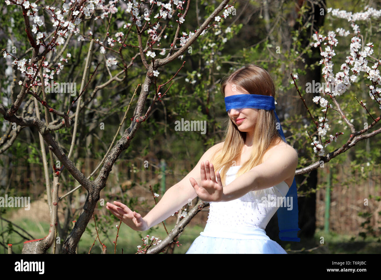 La saison des cerisiers en fleur dans le jardin botanique de Moscou. Jeune fille aux yeux bandés sur fond d'arbre sakura, loisirs au printemps Banque D'Images