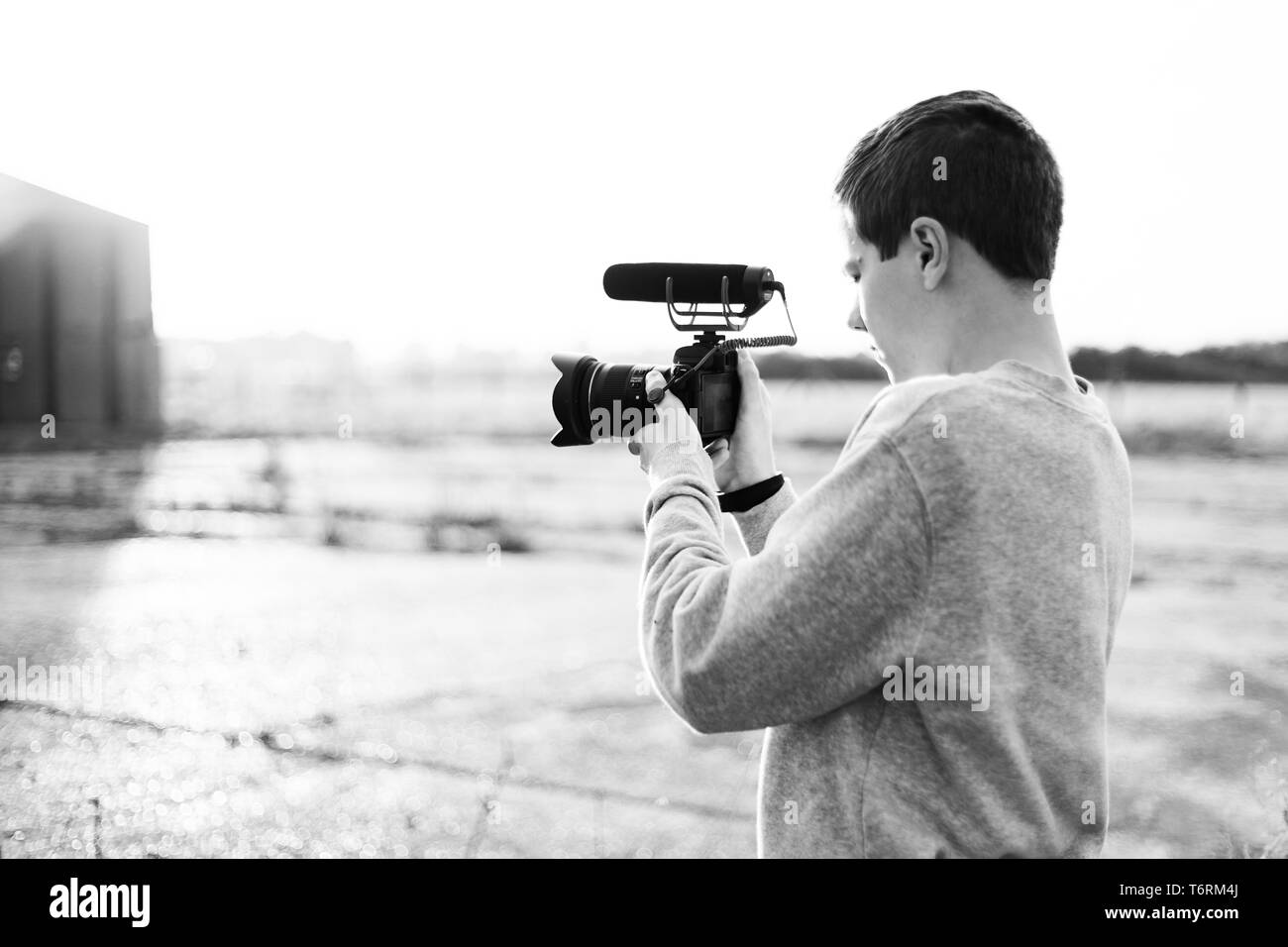 Les jeunes vidéastes l'étude et l'utilisation de caméra avec microphone mirrorless joint pour créer une vidéo. Coucher du soleil de bougies met en évidence le contraste. Banque D'Images