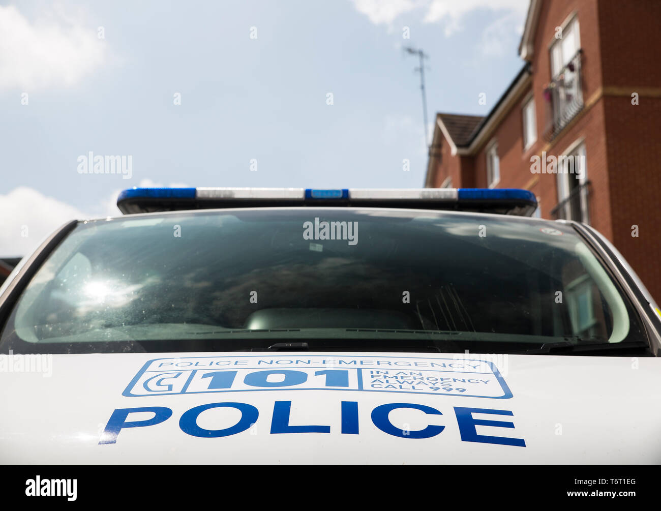 Vue de face rapprochée d'un pare-brise de voiture de police avec un signe de service de police local 101 non urgent écrit sur le capot de la voiture. Banque D'Images