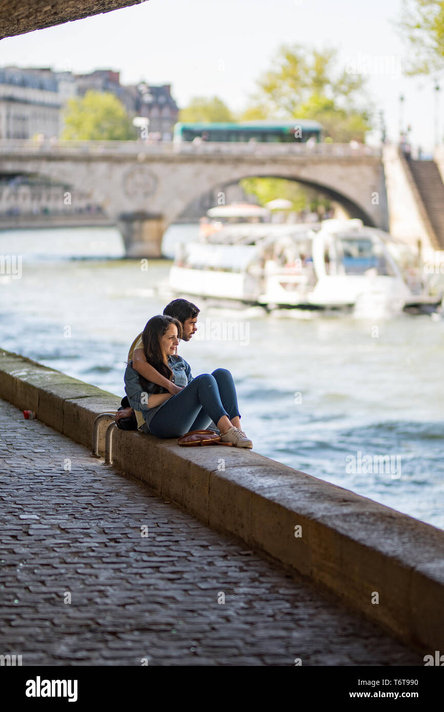 Un jeune couple assis sur la berge de la Seine Banque D'Images