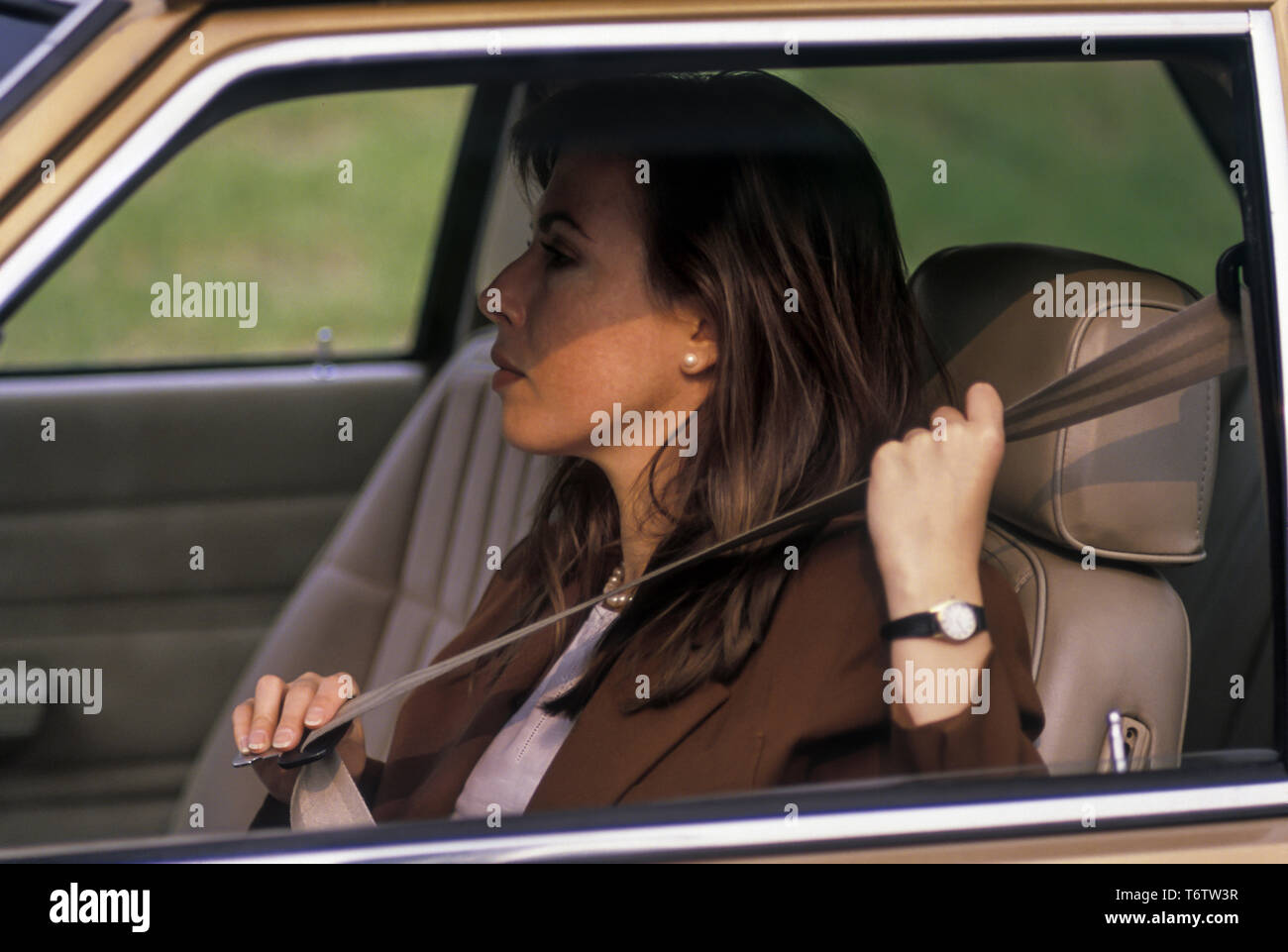 1988 EMPLOYÉ DE BUREAU HISTORIQUE ASSIS DANS LE SIÈGE DU CONDUCTEUR DE L'AUTOMOBILE MISE SUR LA CEINTURE DE SIÈGE Banque D'Images