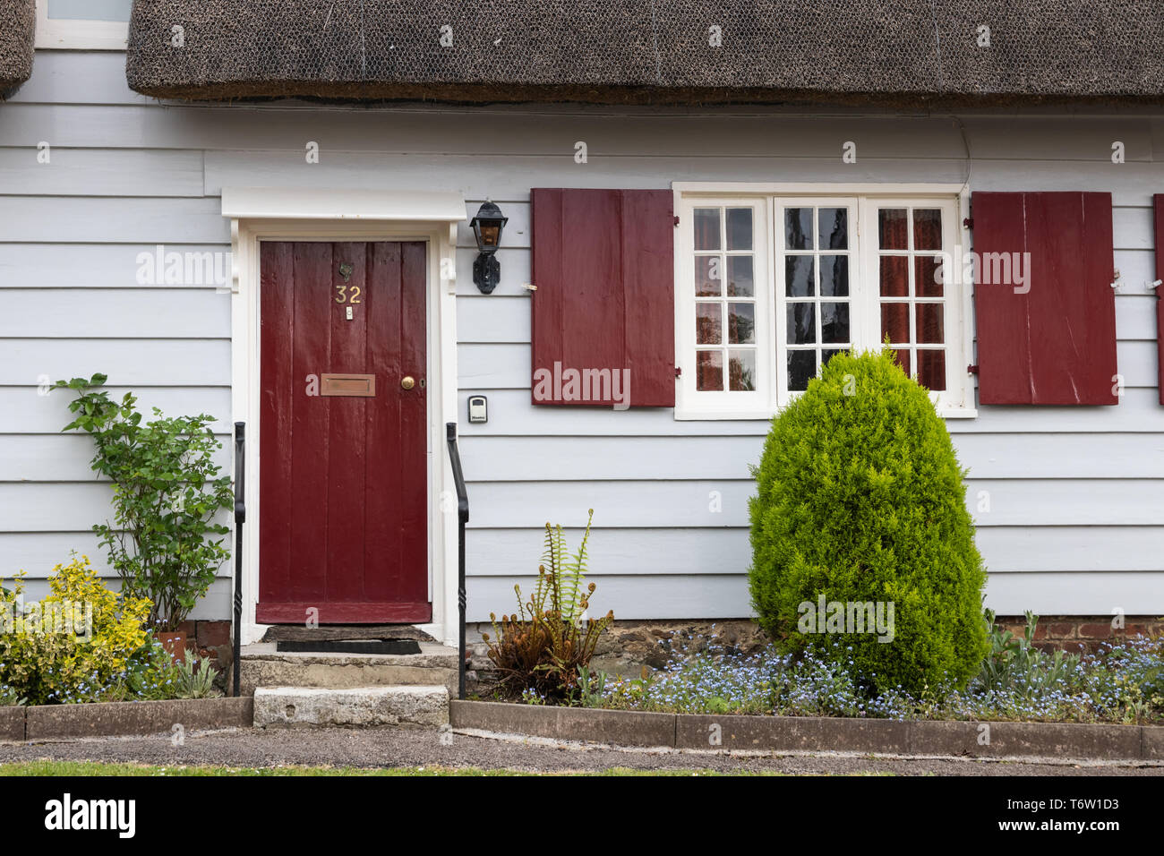 Thatched cottage anglais traditionnel avec entrée porte rouge Banque D'Images