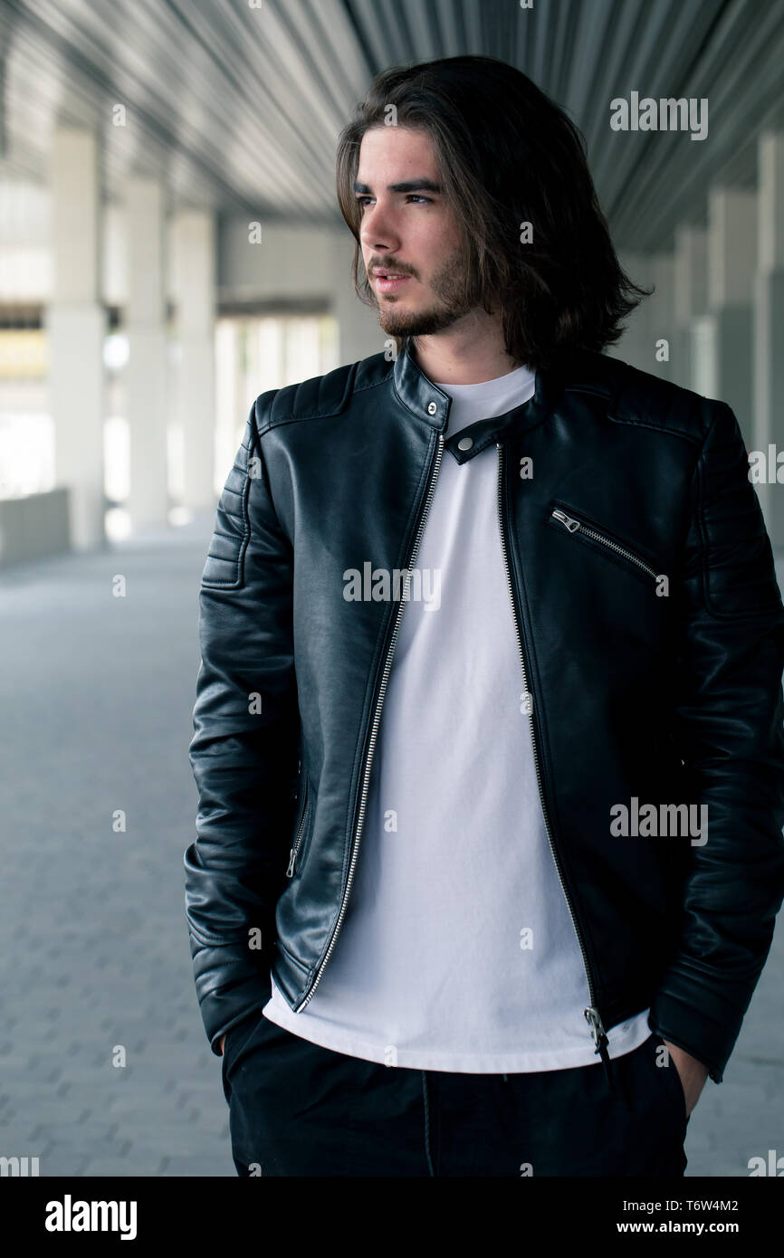 Portrait de demi-longueur beau barbu habillé dans des vêtements à la mode dans la rue alors que l'article contre mur avec pour contenu publicitaire. Hipster beau mec posant sur copy space Banque D'Images