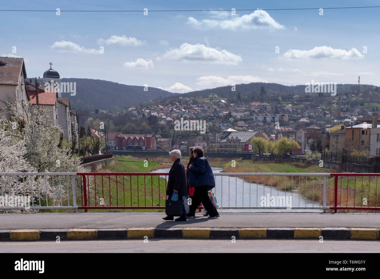 SIGHISOARA, Roumanie - le 9 avril 2019 : trois vieilles dames marche sur le pont sur la rivière Tarnava à Sighisoara. Vue vers les tours de vieux bâtiments Banque D'Images