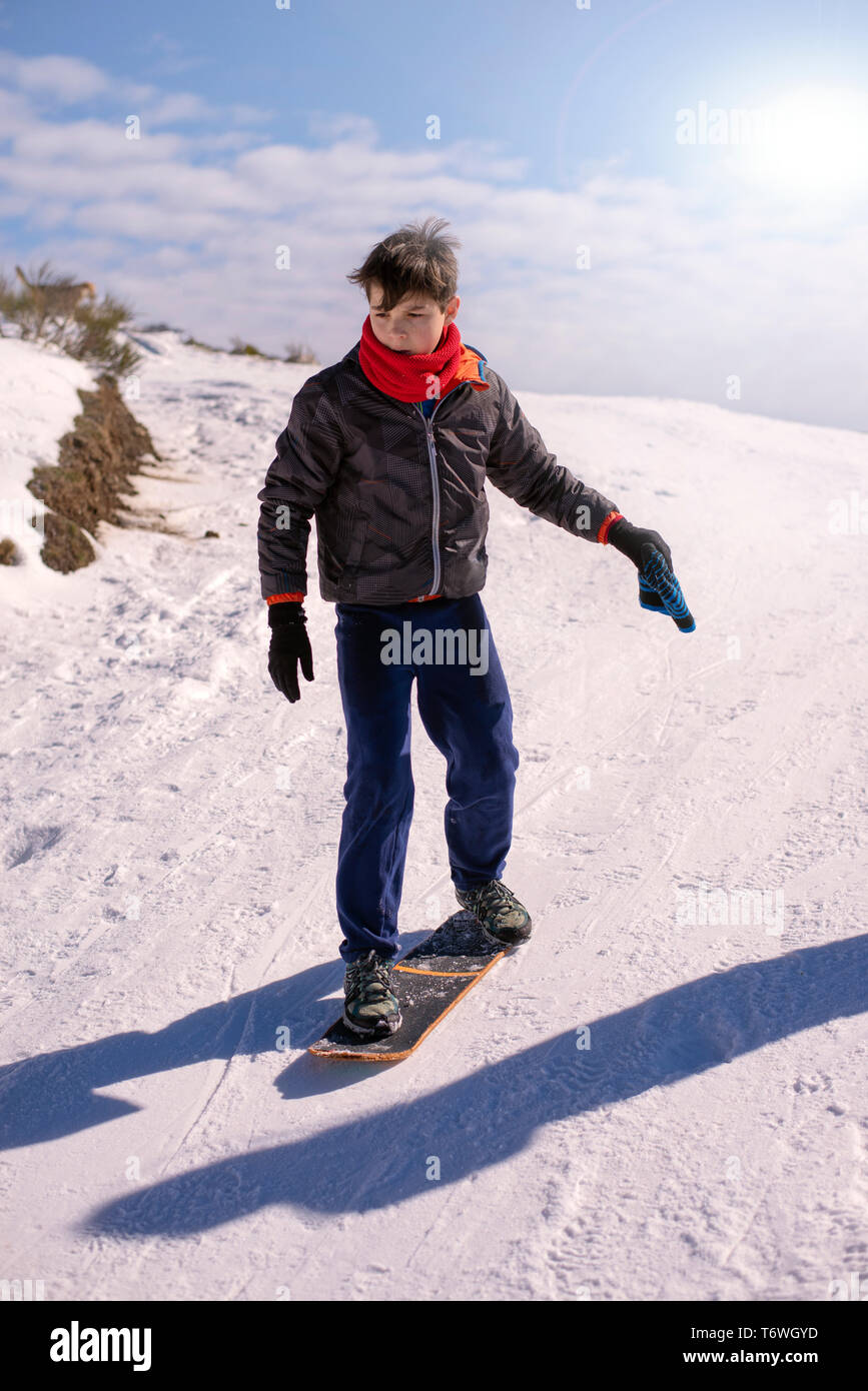 Vue avant du garçon de la planche à roulettes dans une colline couverte de neige Banque D'Images