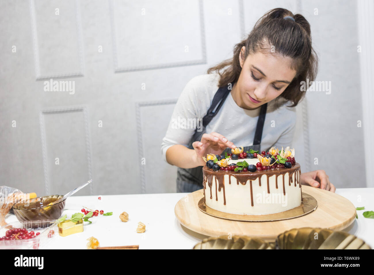 Un Patissier Est A Cote D Un Petit Biscuit Gateau Avec La Creme Blanche Decore Avec Du Chocolat Et De Petits Fruits Cake Se Dresse Sur Un Support En Bois Sur Fond Blanc