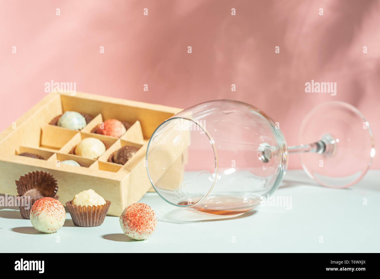 Un verre de champagne ou de vin, une boîte de chocolats fabriqués à partir  de chocolat blanc et noir sur fond rose est une lumière vive Photo Stock -  Alamy