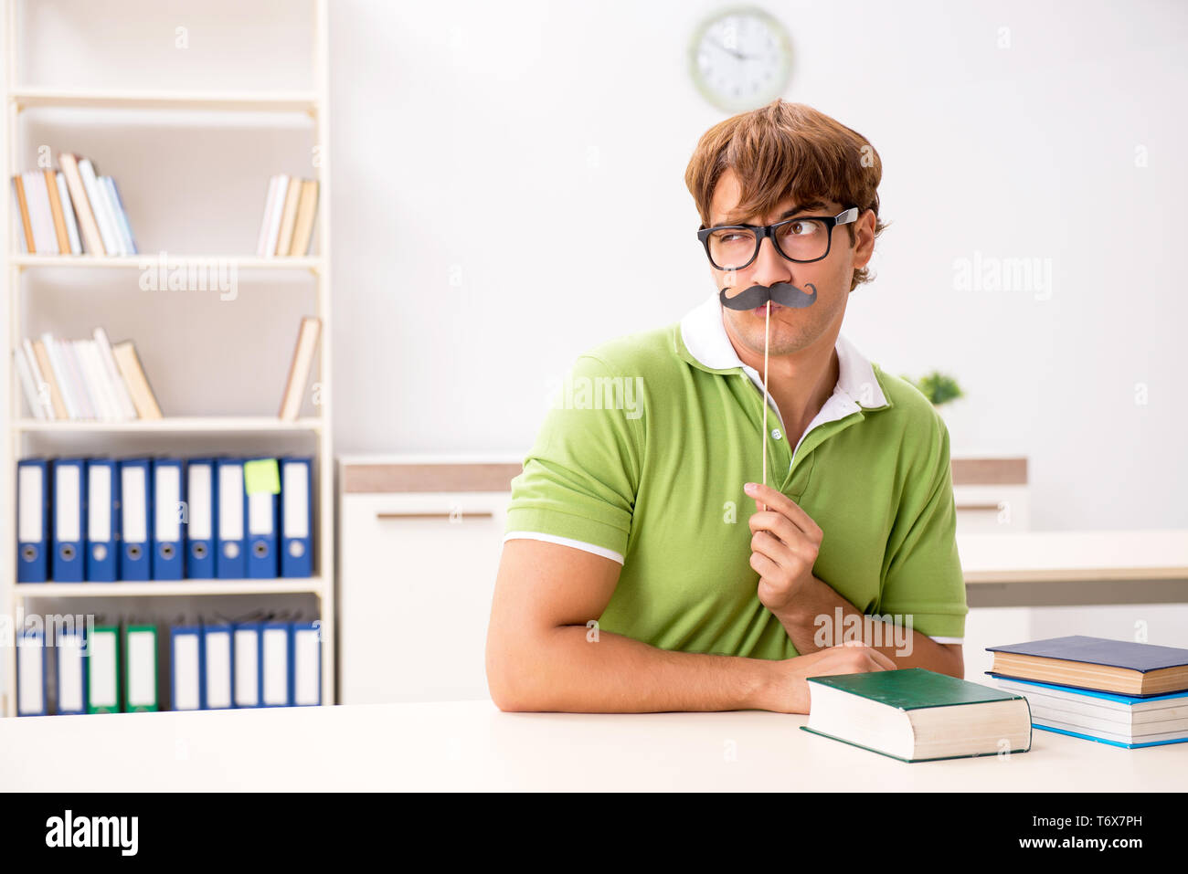 Étudiant avec fake moustache reading book Banque D'Images