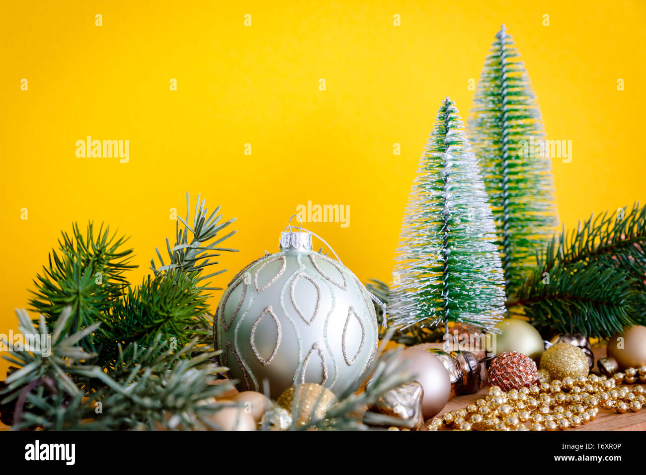 Boules de verre de décoration de Noël avec sapins sur fond jaune Banque D'Images