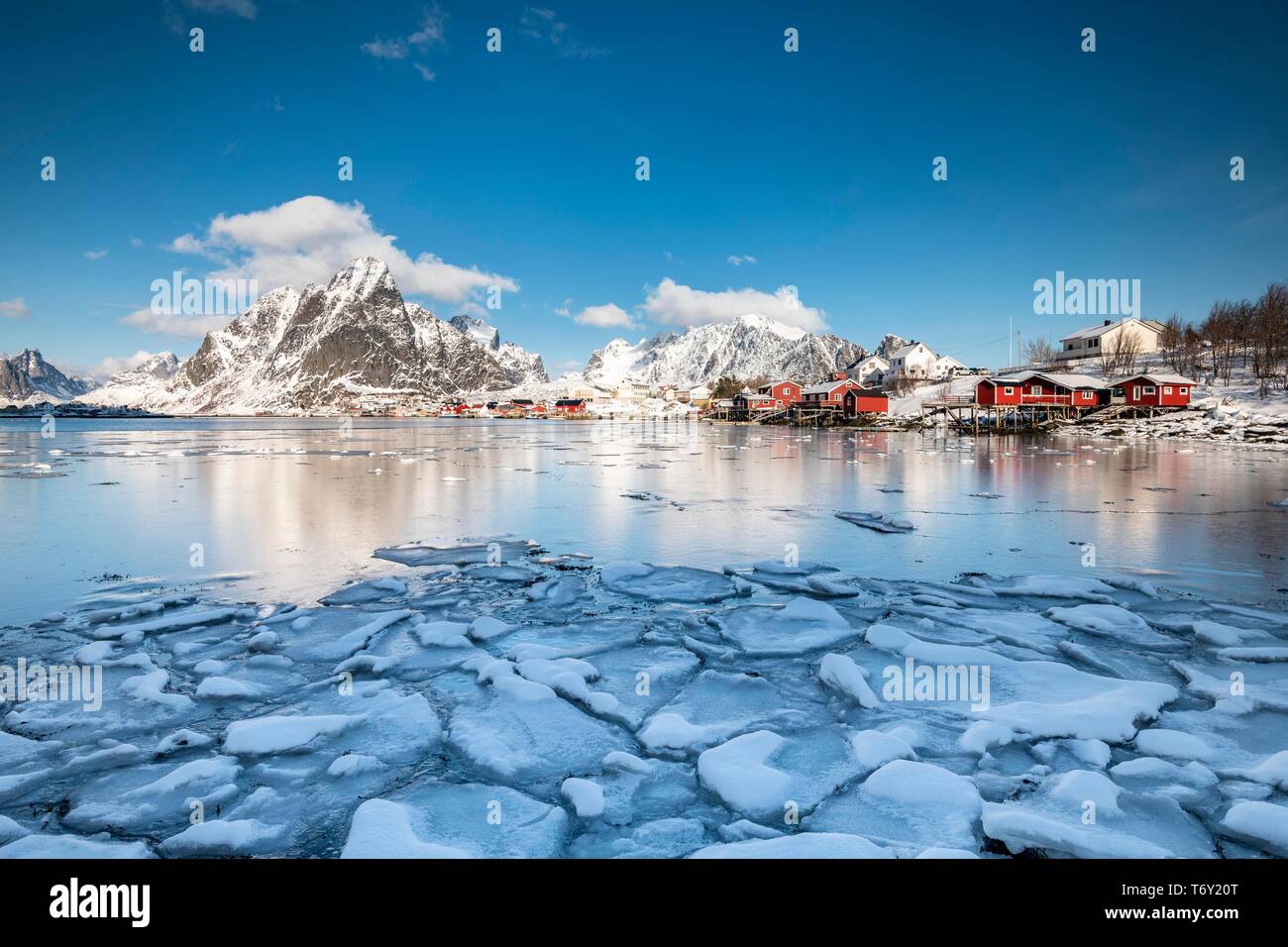 Cabines par le fjord avec des blocs de glace à l'avant-plan, village de pêcheurs Reine, Olstinden, Moskenesoya, Lofoten, Norvège Banque D'Images