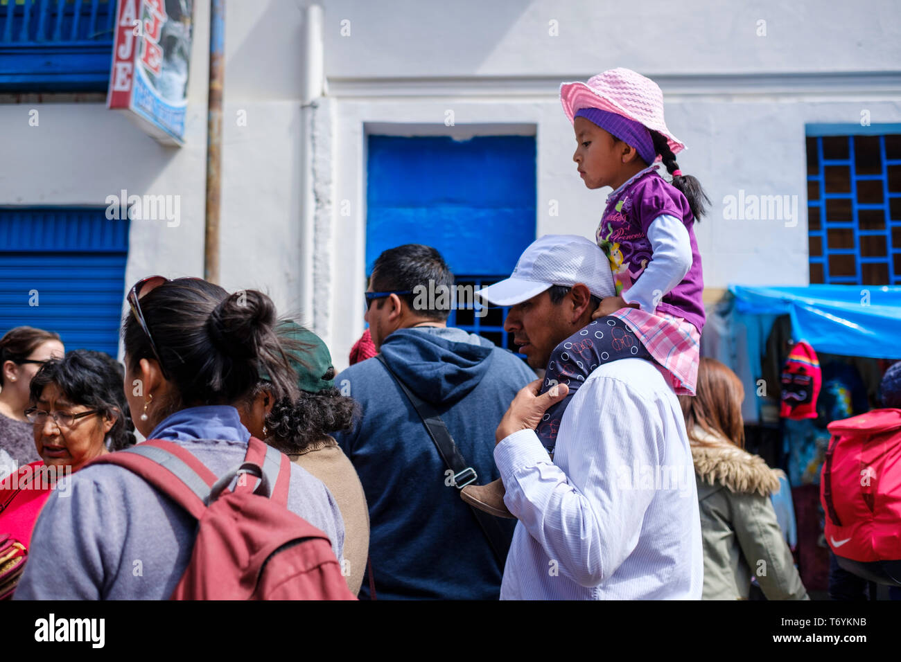 Fille sur les épaules de son père sur les rues animées de Paucartambo lors de Festival de la Vierge du Carmen, Pérou Banque D'Images