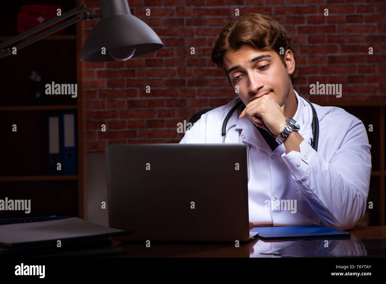 Le jeune beau médecin travaillant la nuit à l'hôpital Banque D'Images