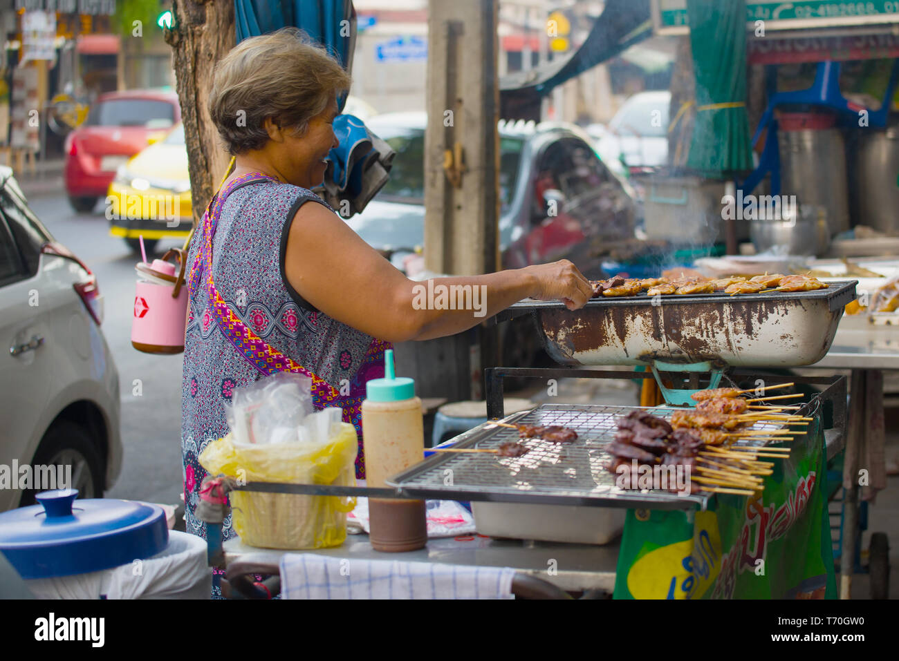 BANGKOK, THAÏLANDE - 27 décembre 2018 : femme frites brochettes de viande sur une rue de la ville. Bangkok Street Food Banque D'Images