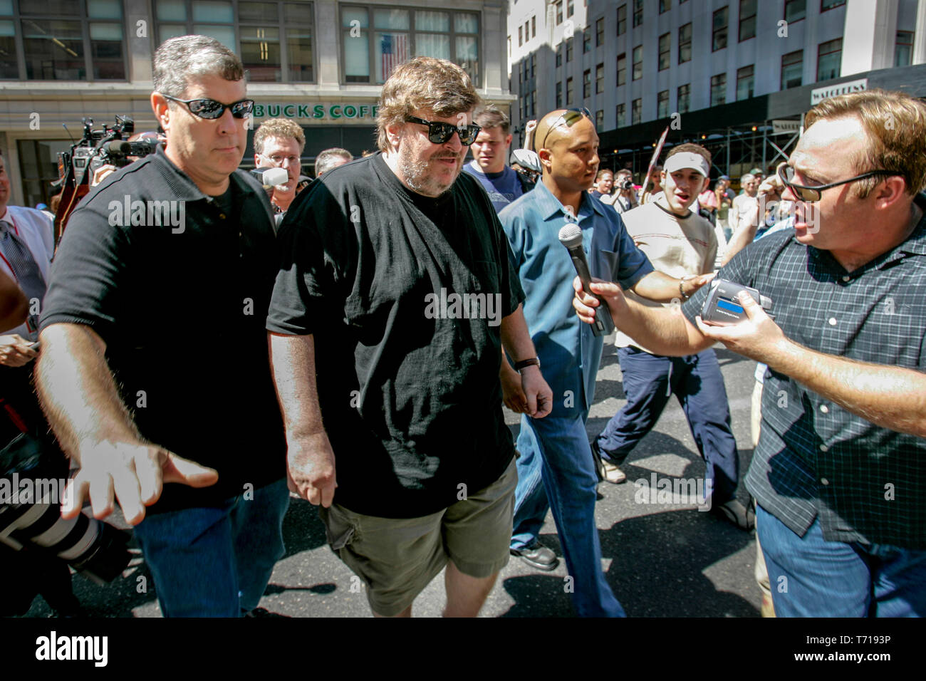 Réalisatrice de documentaires et auteur Michael Moore est escorté par des gardes du corps alors qu'il participait à une marche de protestation au cours de la Convention nationale du parti républicain à New York. À la gauche de Moore, choc jock et théoricien de la conspiration Alex Jones tente d'interviewer Moore. Banque D'Images