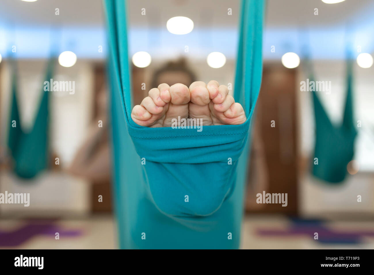 Libre de jambes en hamac pour voler les exercices de yoga. Femme faisant voler les étirements de yoga dans une salle de sport. Mettre en place et mieux-être. Banque D'Images