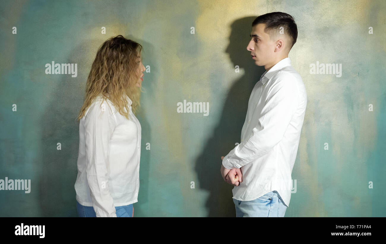 Jeune couple mari et femme se disputent et crier les uns les autres debout près du mur, vue de côté. Banque D'Images