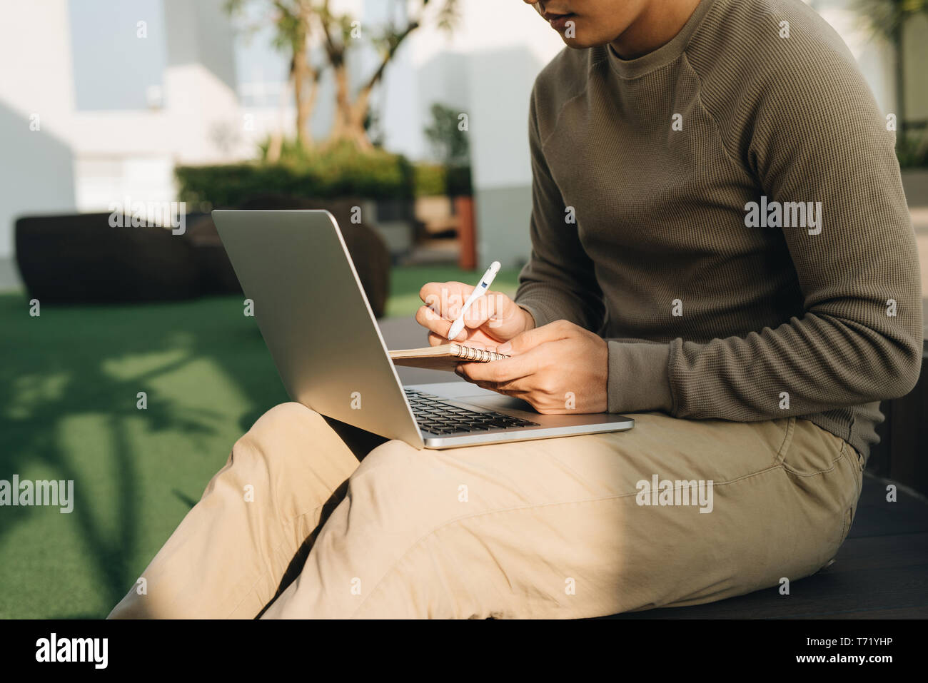 Un homme assis à l'ordinateur portable sur ses genoux et l'écriture de l'ordinateur portable Banque D'Images
