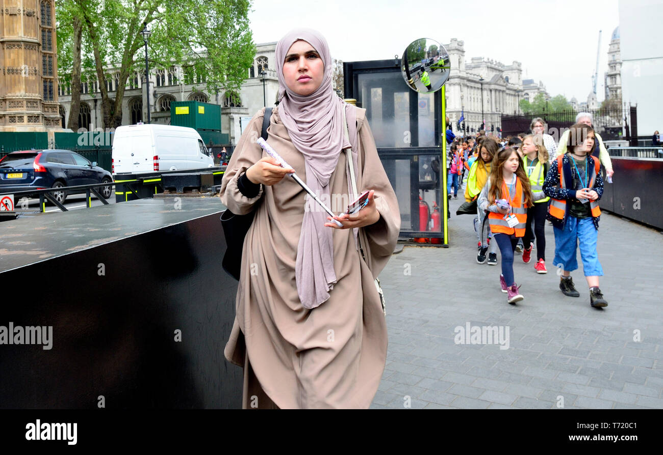 Londres, Angleterre, Royaume-Uni. Femme en robe islamique avec son téléphone portable par les Chambres du Parlement Banque D'Images