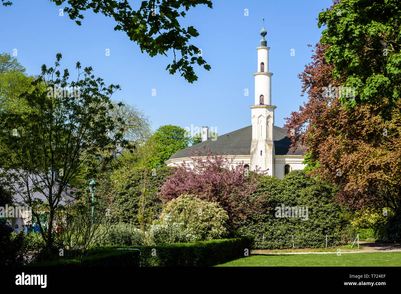 Le minaret de la grande mosquée de Bruxelles, Belgique, dépassant au-dessus des buissons dans le Parc du Cinquantenaire au printemps. Banque D'Images