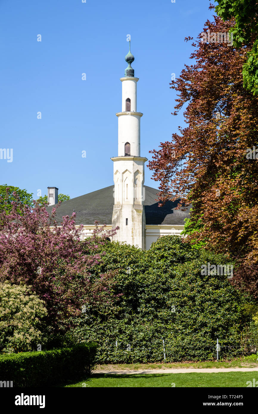 Le minaret de la grande mosquée de Bruxelles, Belgique, dépassant au-dessus des buissons dans le Parc du Cinquantenaire au printemps. Banque D'Images