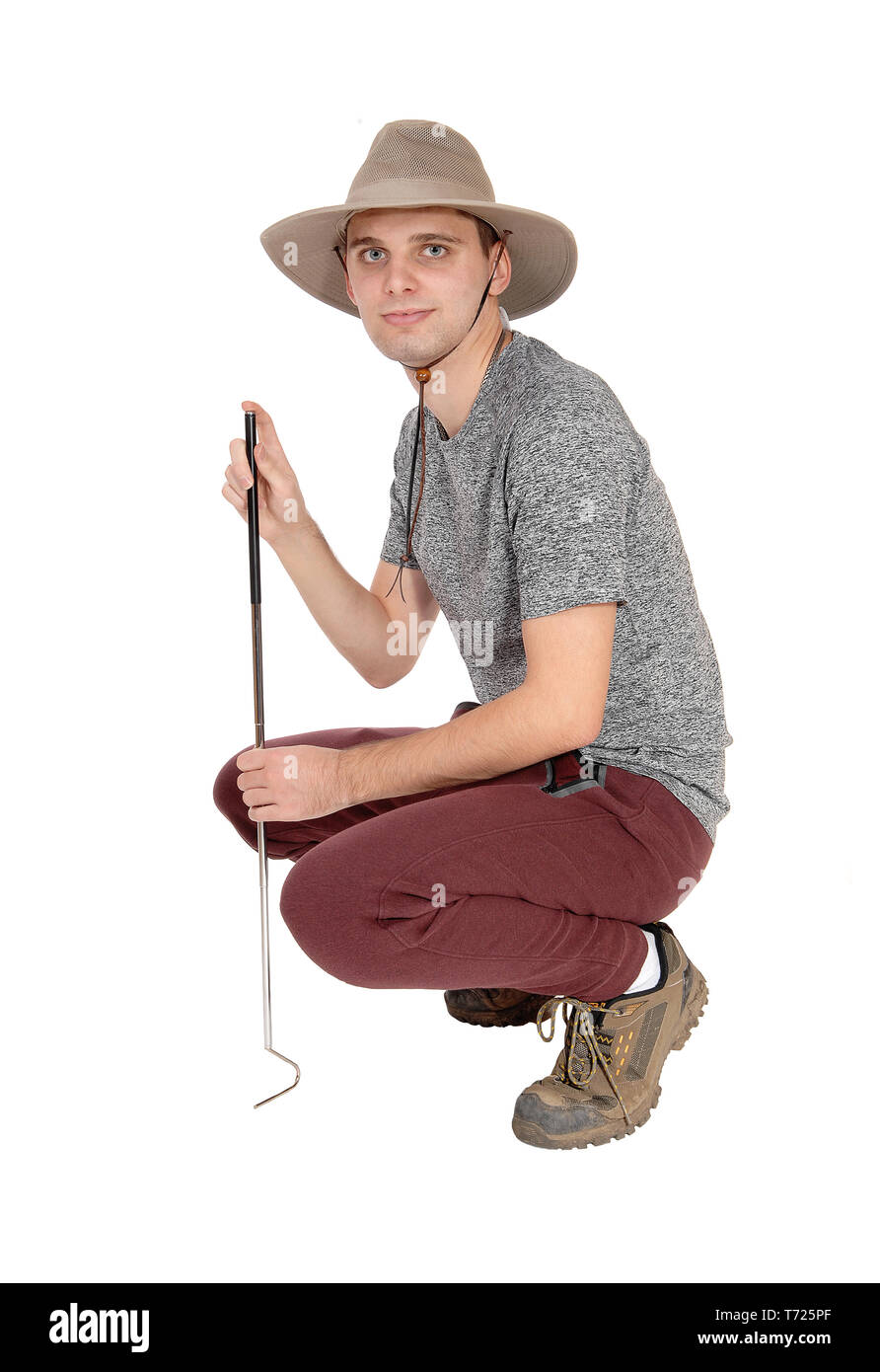 Jeune homme accroupi dans safari hat Banque D'Images