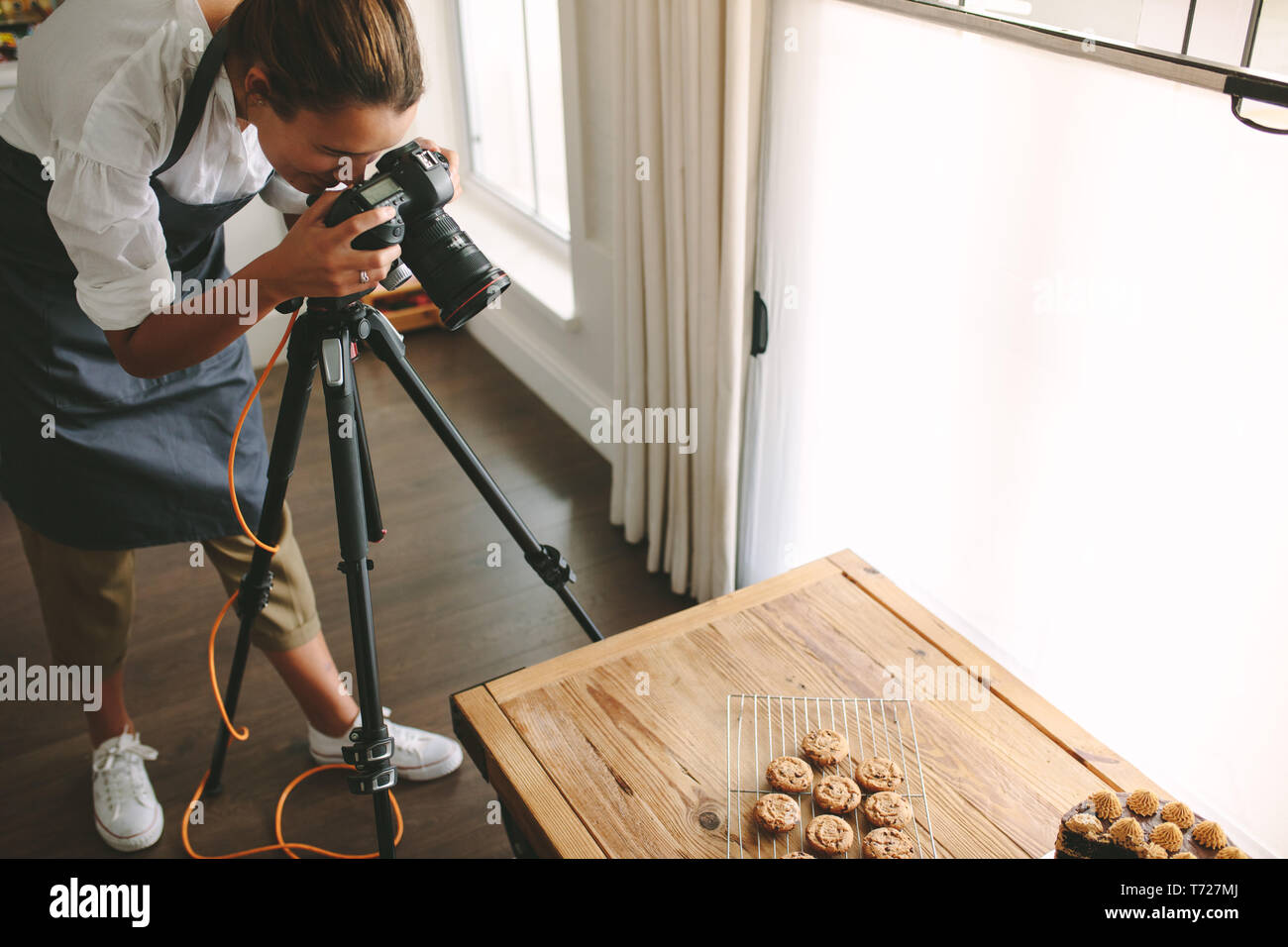 Femme chef de prendre des photos de dessert sur table avec votre appareil photo reflex numérique monté sur trépied. Femme prendre des photos d'aliments sucrés pour son blog. Banque D'Images