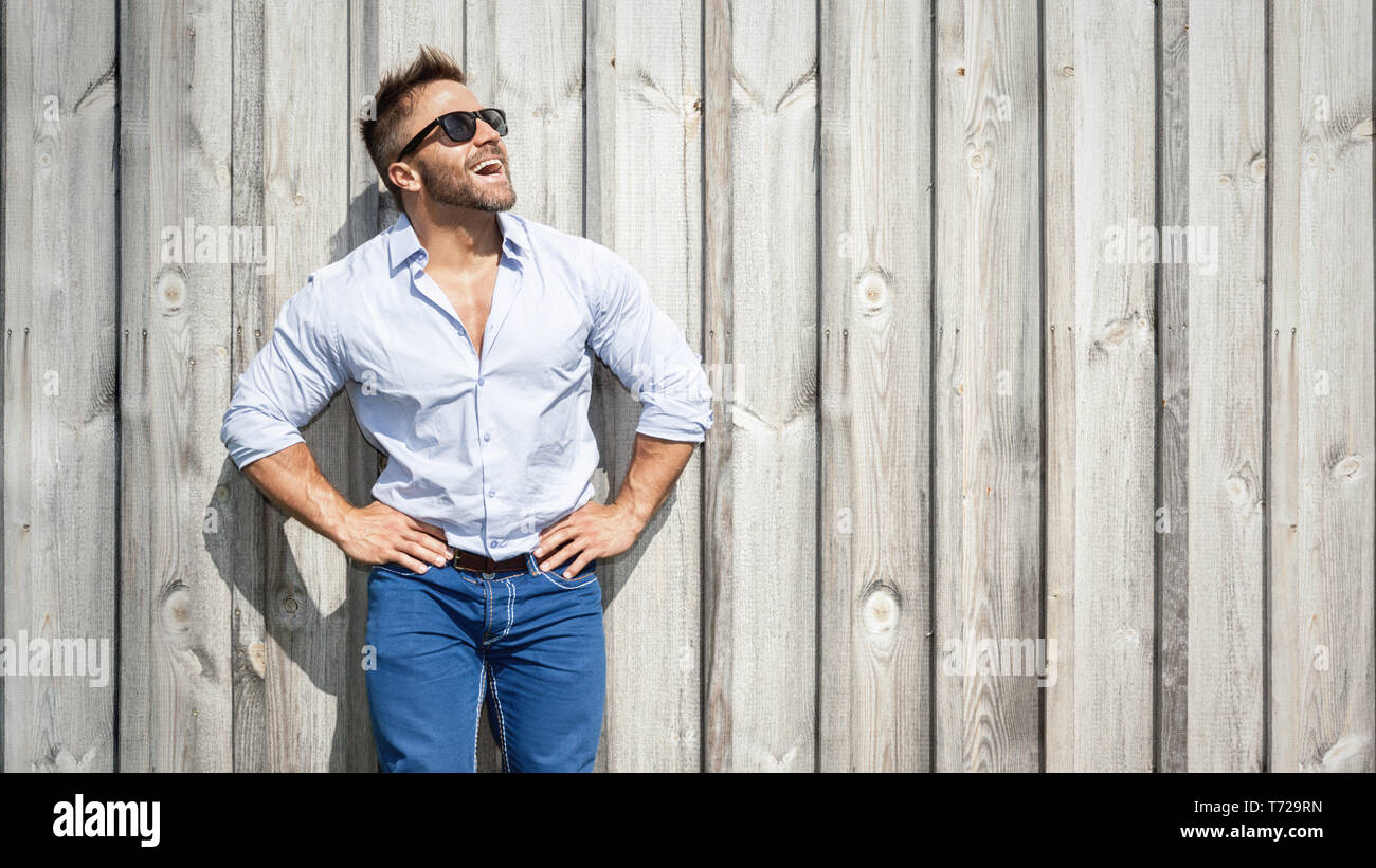 Homme barbu avec des lunettes à un mur en bois Banque D'Images