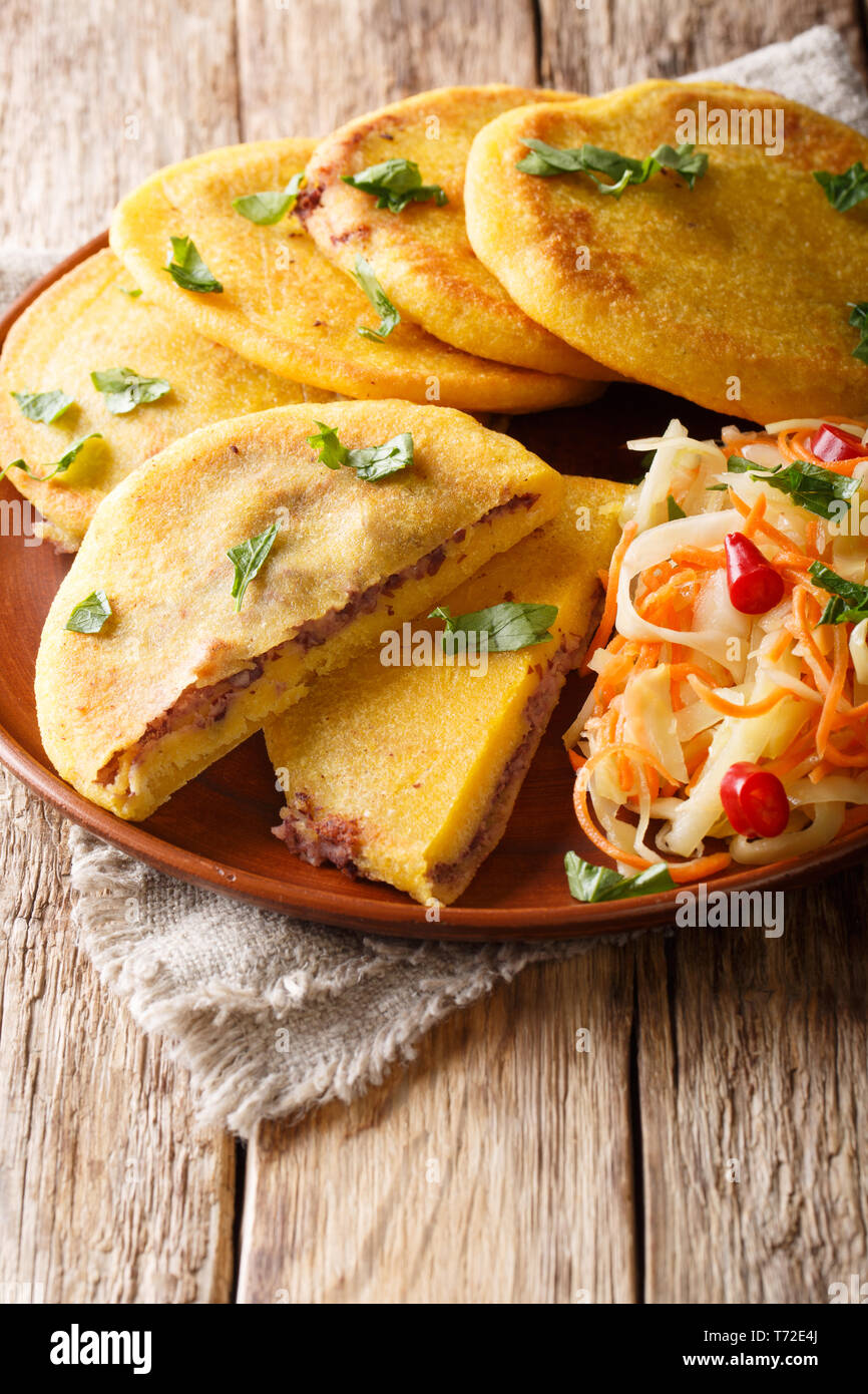Sex fried pupusa servi avec curtido libre sur une plaque sur la table verticale. Banque D'Images