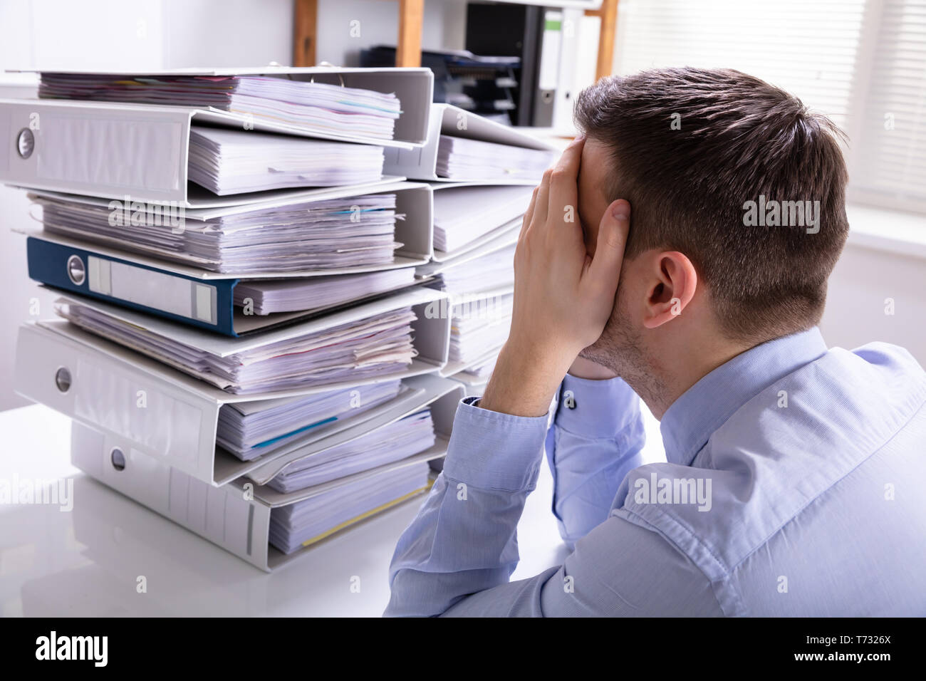 Vue arrière du souligné Businesswoman Pointing en face de dossiers empilés Banque D'Images