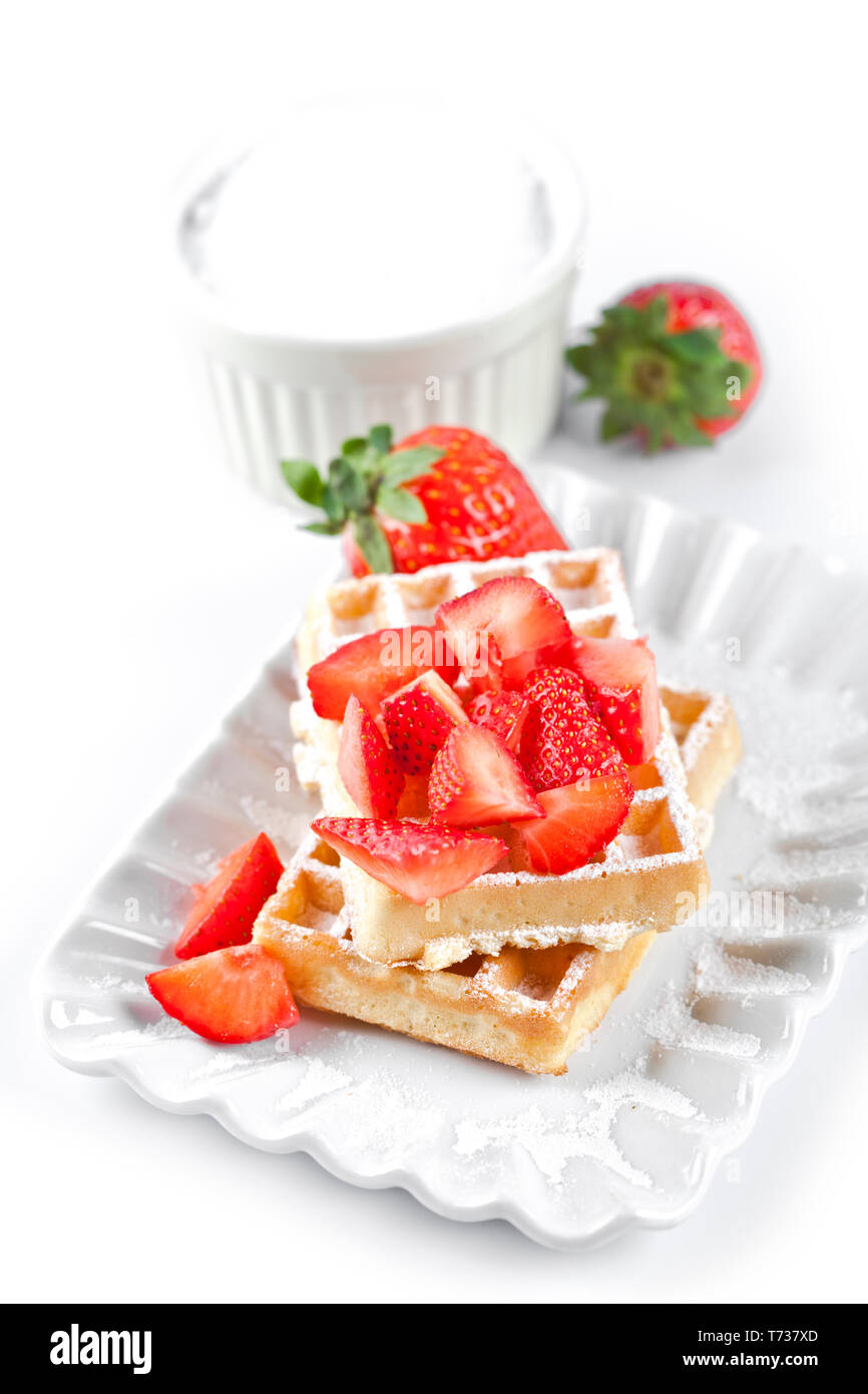Belgique waffers avec du sucre en poudre et les fraises sur une plaque en céramique sur le tableau blanc. Des wafers. Banque D'Images