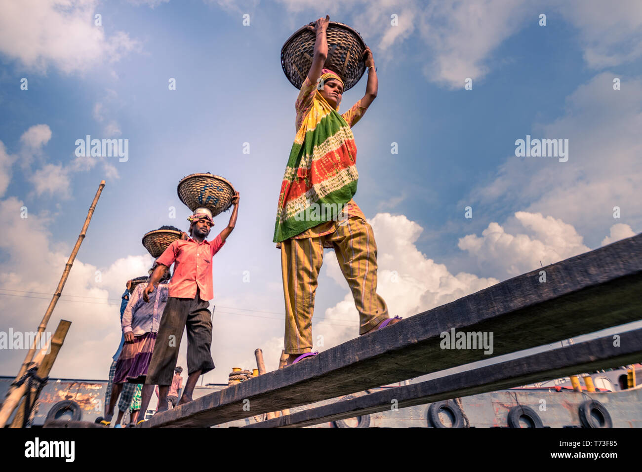 Station d'hommes et femmes de travailleurs sont considérés comme ils décharger le charbon avec des paniers de bambou de ferries au port de la rivière Buriganga à Dhaka, au Bangladesh. Banque D'Images