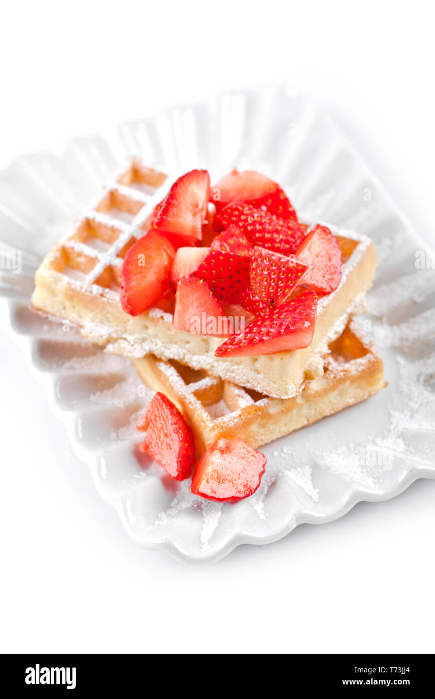 Belgique waffers avec du sucre en poudre et les fraises sur une plaque en céramique sur le tableau blanc. Des wafers. Banque D'Images