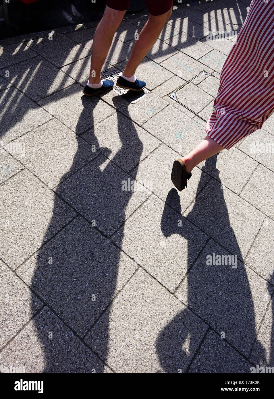 Les jambes des piétons avec ombres sur le pavé Banque D'Images