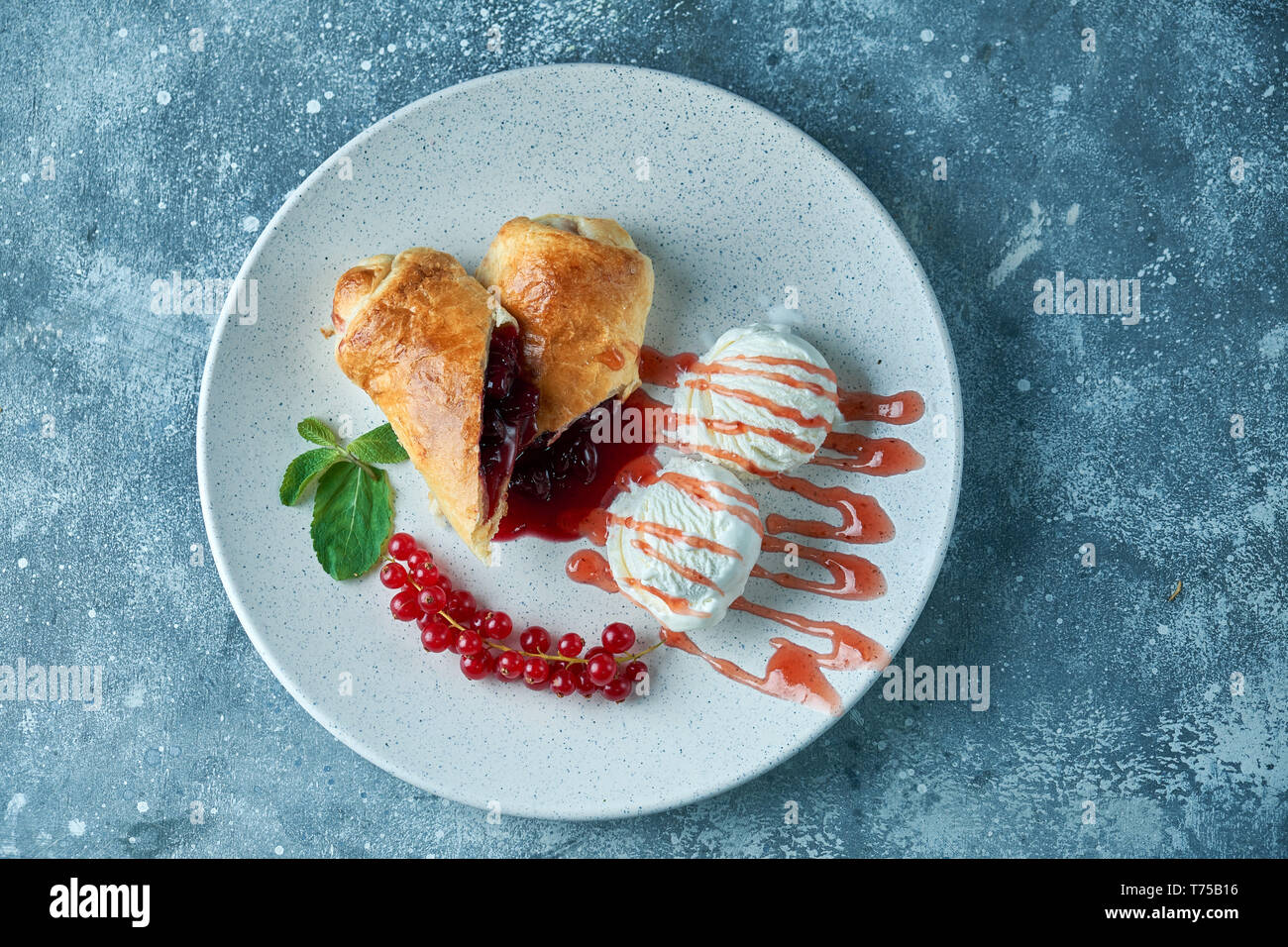 Des tranchées d'un strudel aux fruits rouges frais servi avec des baies de cassis et le sucre en poudre sur une vieille plaque de fond sur un pic avec de la crème glacée Banque D'Images