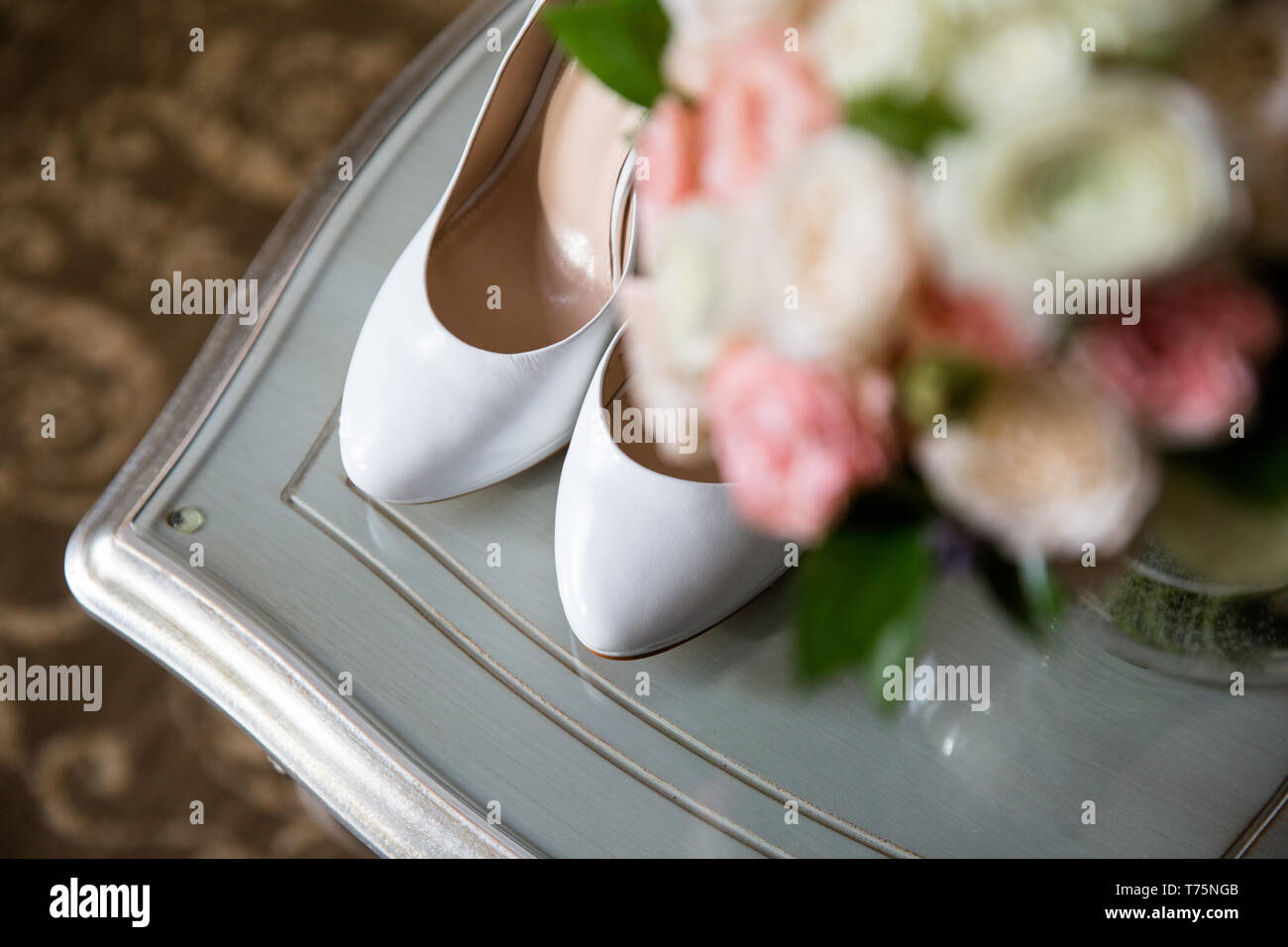 Chaussures de la mariée sur un arrière-plan flou d'un bouquet de mariage Banque D'Images