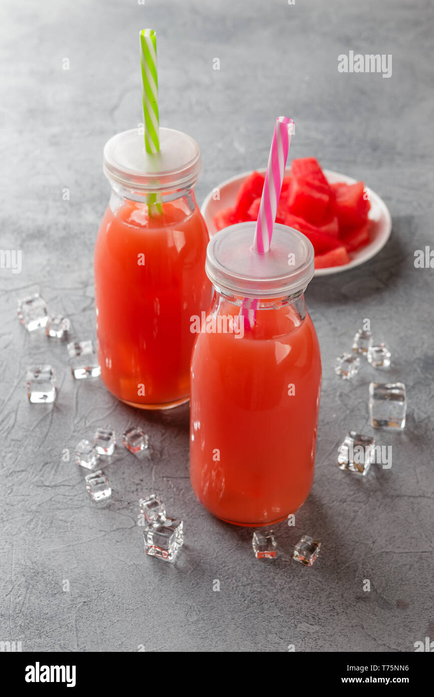 Watermelon drink avec de la glace dans des bouteilles sur fond de béton gris Banque D'Images