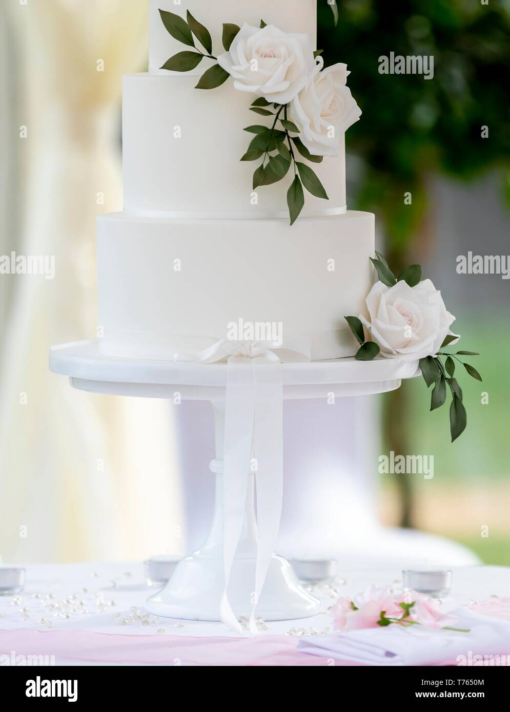 Close up of minimaliste élégant gâteau de mariage décoré avec des roses blanches sur une table dans un chapiteau d'été. Banque D'Images