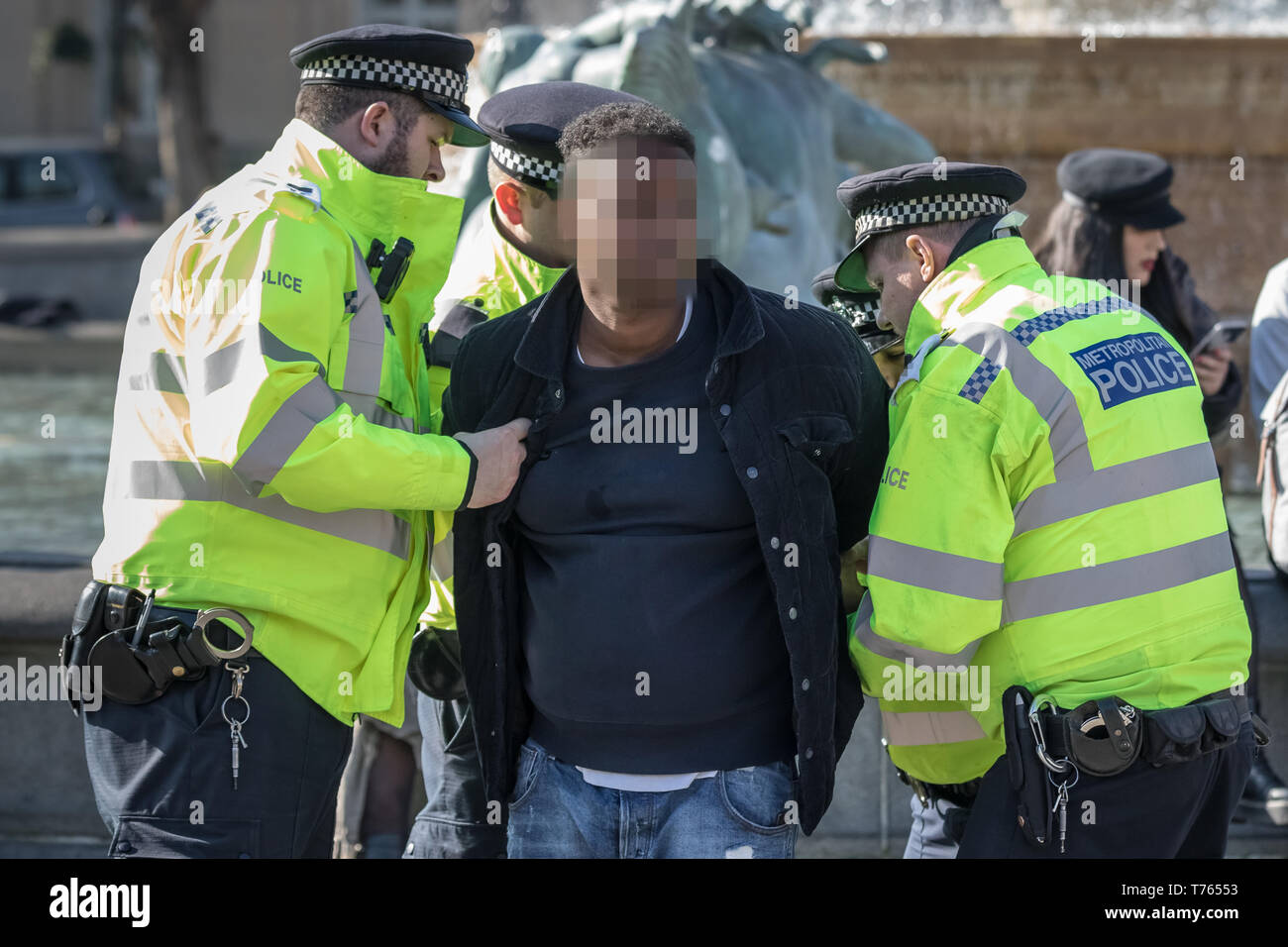 Un jeune homme noir est arrêté et fouillé pendant midi par quatre policiers se sont réunis à Trafalgar Square, Londres, Royaume-Uni. Banque D'Images