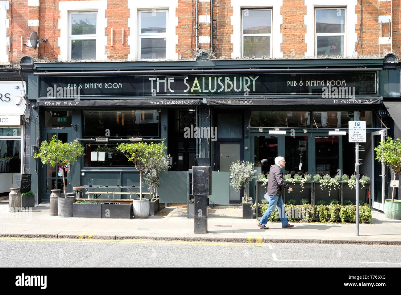 Un homme marche dernières Salusbury pub à Queens Park, au nord de Londres. Banque D'Images
