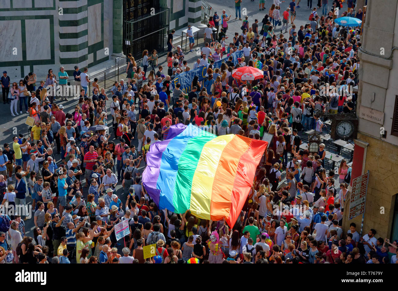 Une vue sur un gay pride 2016 mars entrant dans la Piazza del Duomo de Florence (Firenze), l'Italie, avec un grand drapeau arc-en-ciel porté par le corwd Banque D'Images